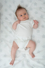 Top view of newborn babygirl lying on bed.