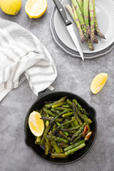 Fresh green roasted asparagus in black iron pan. Healthy, vegan food.