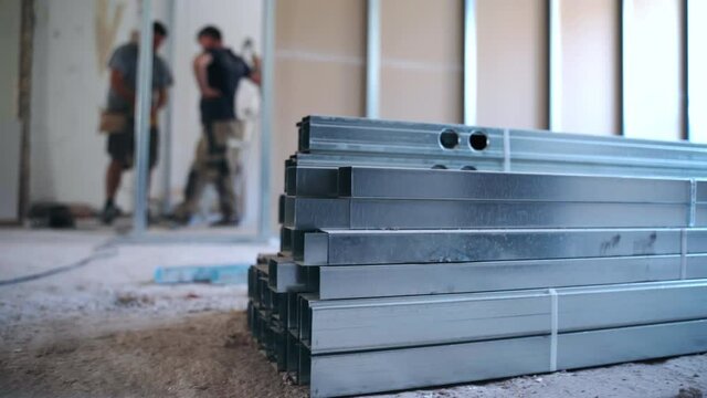 Teamwork concept, male builders working on new apartmen construction site, making measurements and installing metal profiles and drywalls. Workers reconstructing apartment, remodeling walls and