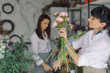 Florist arranging bouquet with pink peonies in flower shop. Summer wedding flowers.