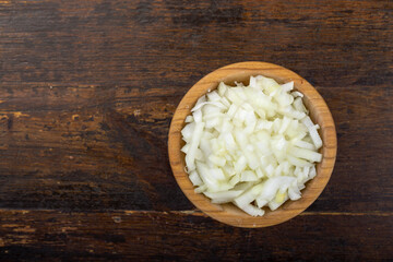 Sliced raw onion in a bowl on a wooden background. Vegetable, ingredient and staple food.