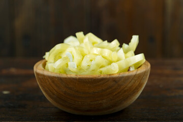 Sliced raw yellow peppers in a bowl on a wooden background. Vegetable, ingredient and staple food.