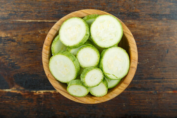 Sliced zucchini in a bowl on a wooden background. Vegetable, ingredient and staple food.