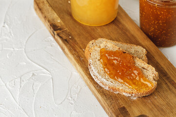 Slice of bread covered with fruit jam on wooden board