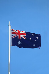Realistic Australian flag on a pole against a blue sky - Australia Day