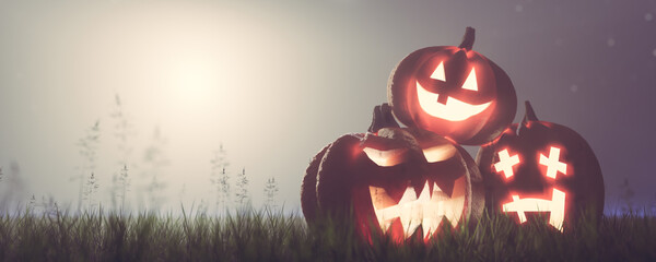 Halloween pumpkins on grass at foggy night.