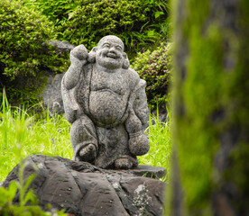 Decorative stone statue of  the "Laughing Buddha" a semi-historical Chinese monk who is always depicted laughing with a protruding belly. Name is Budai in Chinese or Hotei in Japanese Buddhism. 