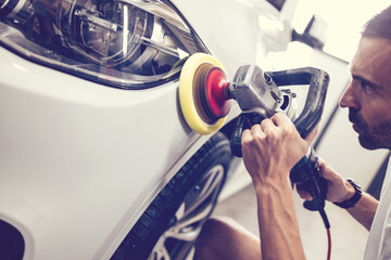 Car detailing - Hands with orbital polisher in auto repair shop. Selective focus.