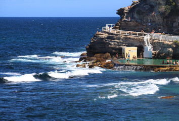 Rock pool under cliff face along side the ocean and waves. Bronte beach, Sydney Australia