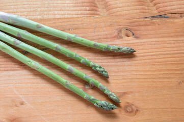 set of four fresh green asparagus isolated on wooden board background