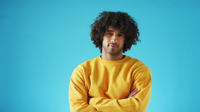 Studio portrait of young man whose expression and mood changes from serious to happy and laughing against blue background - shot in slow motion