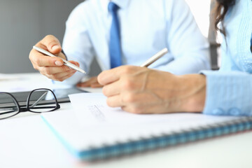 Female and male hands hold pens in office over documents. Small and medium business development concept