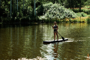 Fototapeta na wymiar SUP. Stand up paddle. Fun on the lake a hot summer day.