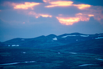 Pink skies and tranquil scenery over mountains in norway during sunset and blue hour.