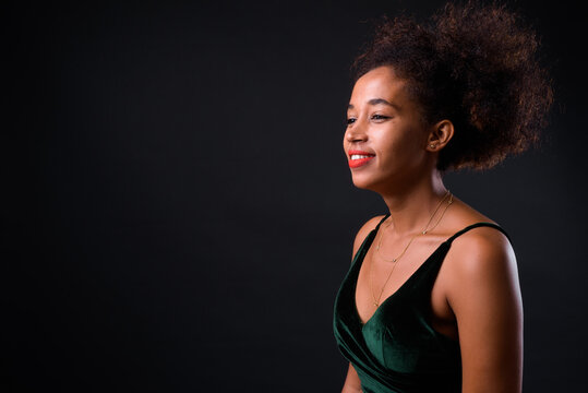 Young beautiful African woman with Afro hair against black background