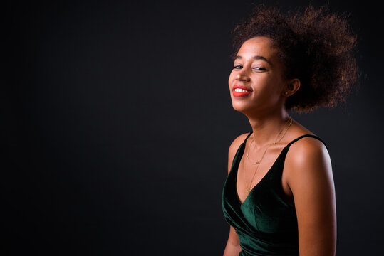 Young beautiful African woman with Afro hair against black background