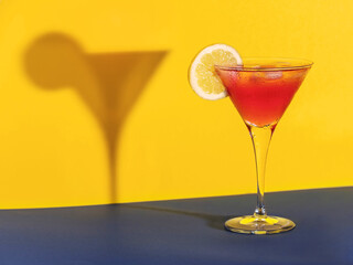 Red cocktail in a glass shaping its shadow on the background