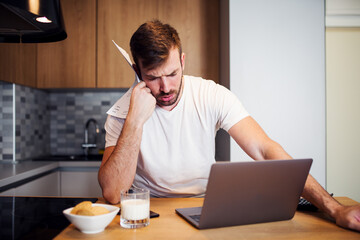 Worried man paying bills online at home