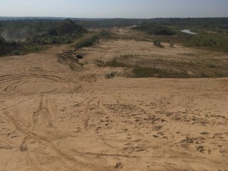 general shot of sand dunes with car tire marks and light vegetation