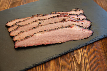 slices of beef brisket on a black plate on a wooden table 