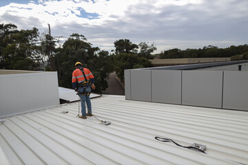 Trained competent industrial construction worker wearing safety helmet fall arrest harness and...