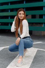 Stylish girl posing at the street, dressed in blue jeans and a white T-shirt