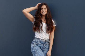 Portrait of smiling pretty girl. Beautiful young woman with backpack posing on a blue wall