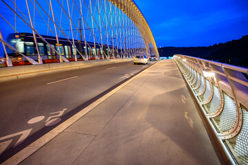 Naklejka premium Cars and a Tram motion blurred as they cross The Troja Bridge, Prague, Czech Republic at night