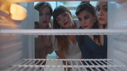 Four beautiful plus size ladies opening empty fridge feeling hungry and upset