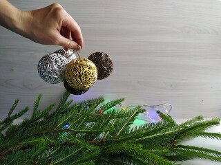 decorate the Christmas tree: Christmas garland and golden carved balls. Woman's hand holds golden and silver carved balls to decorate the christmas tree