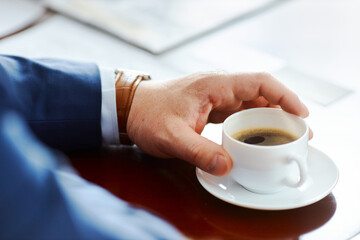 a man's hand of a businessman with a clock holds a mug of coffee early in the morning