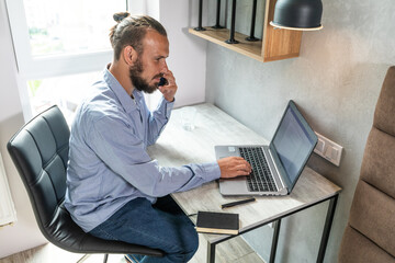 The guy sits at the computer, looks at the phone and replies to call