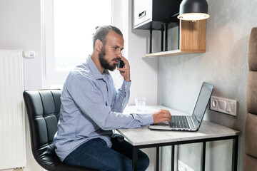 The guy sits at the computer, looks at the phone and replies to call