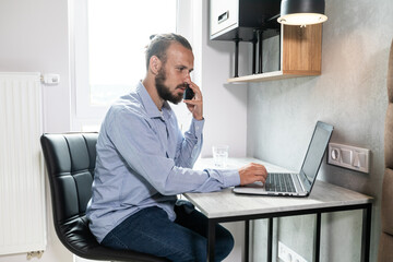The guy sits at the computer, looks at the phone and replies to call