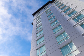 The exterior corner of a tall grey building. The wall is made from metal composite panels. The blue...