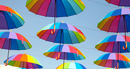 Obraz premium Umbrellas in the color of the rainbow against the sky.
