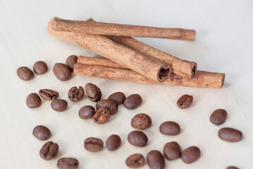 Cinnamon sticks and coffee beans. Roasted coffee beans on a wooden background. Light tree background.