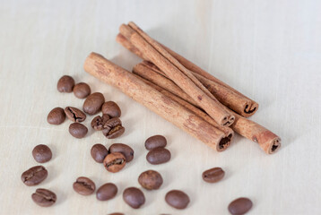 Cinnamon sticks and coffee beans. Roasted coffee beans on a wooden background. Light tree background.
