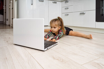 little girl doing gymnastics at home online. doing splits in front of laptop