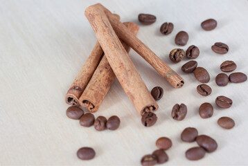 Cinnamon sticks and coffee beans. Roasted coffee beans on a wooden background. Light tree background.