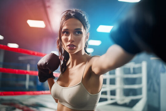 Woman showing hit in boxing gloves.