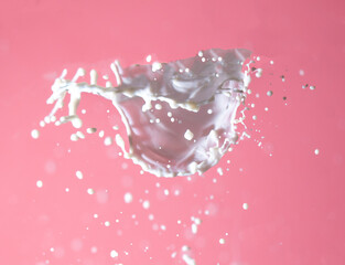 Splashing milk on a pink background.