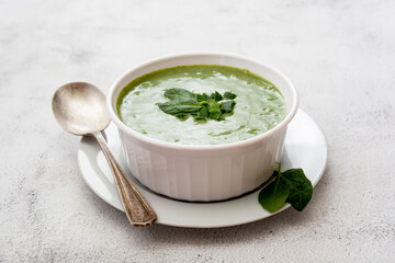 Creamy green spinach soup in a white bowl, spring healthy green creamy soup. Detox, dieting or clean eating food.