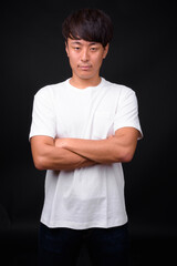 Young handsome Asian man against black background