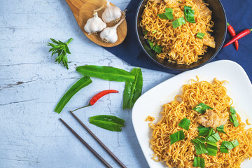 Stir noodles with vegetables in a white plate on a wooden floor.