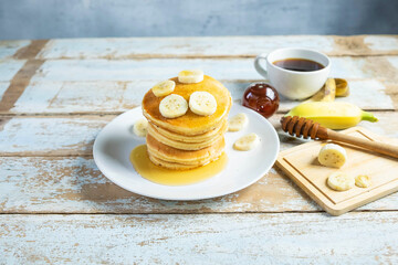 Pancakes topped with honey and bananas on the table