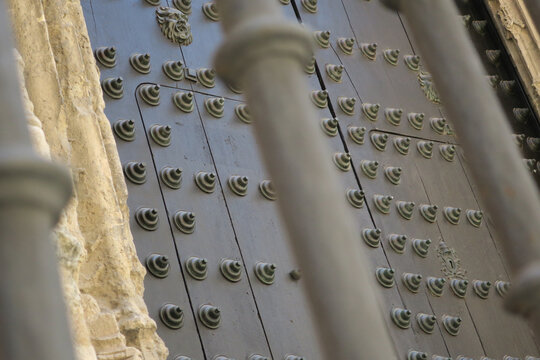entrance, door decorated with iron knobs seen through a fence