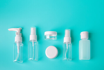Six different plastic bottles or travel kit with flight approved containers laying on vivid blue background. Woman hand luggage and travel concept. Copy space for text.