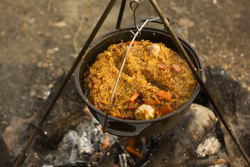 Cooking camping outdoor meal in an open fire in a travel pot with blaze. Dinner during travel.