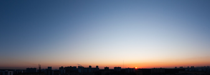 Fototapeta na wymiar Clear blue sky and sun over city, sunset panorama